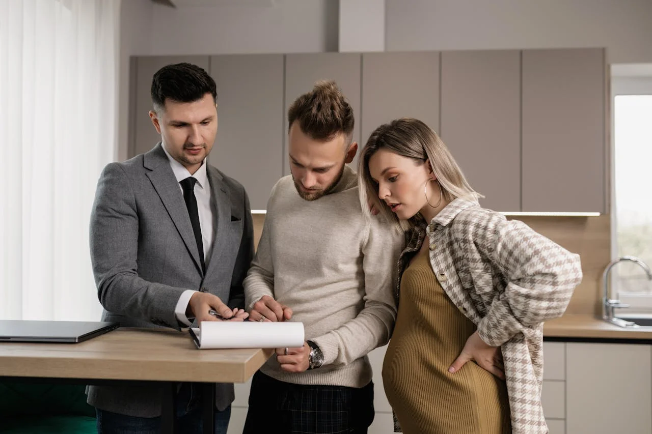 Man in Gray Jacket Showing Documents to a Man and Pregnant Woman